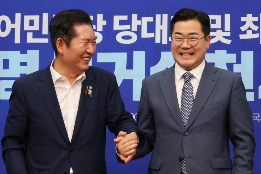 더불어민주당 정청래·박찬대(오른쪽) 당대표 후보가 15일 서울 여의도 국회에서 열린 공명선거 실천 서약식에서 서약문에 서명한 뒤 손을 잡고서 기념촬영 하고 있다. / 연합뉴